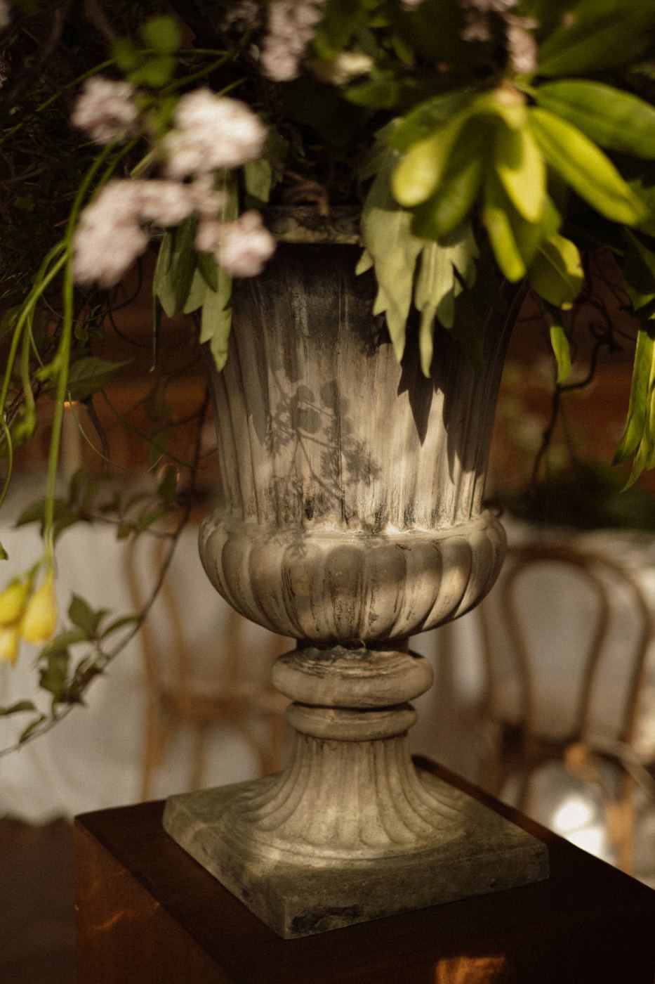 Detail van een stenen urn met bloemen en blad